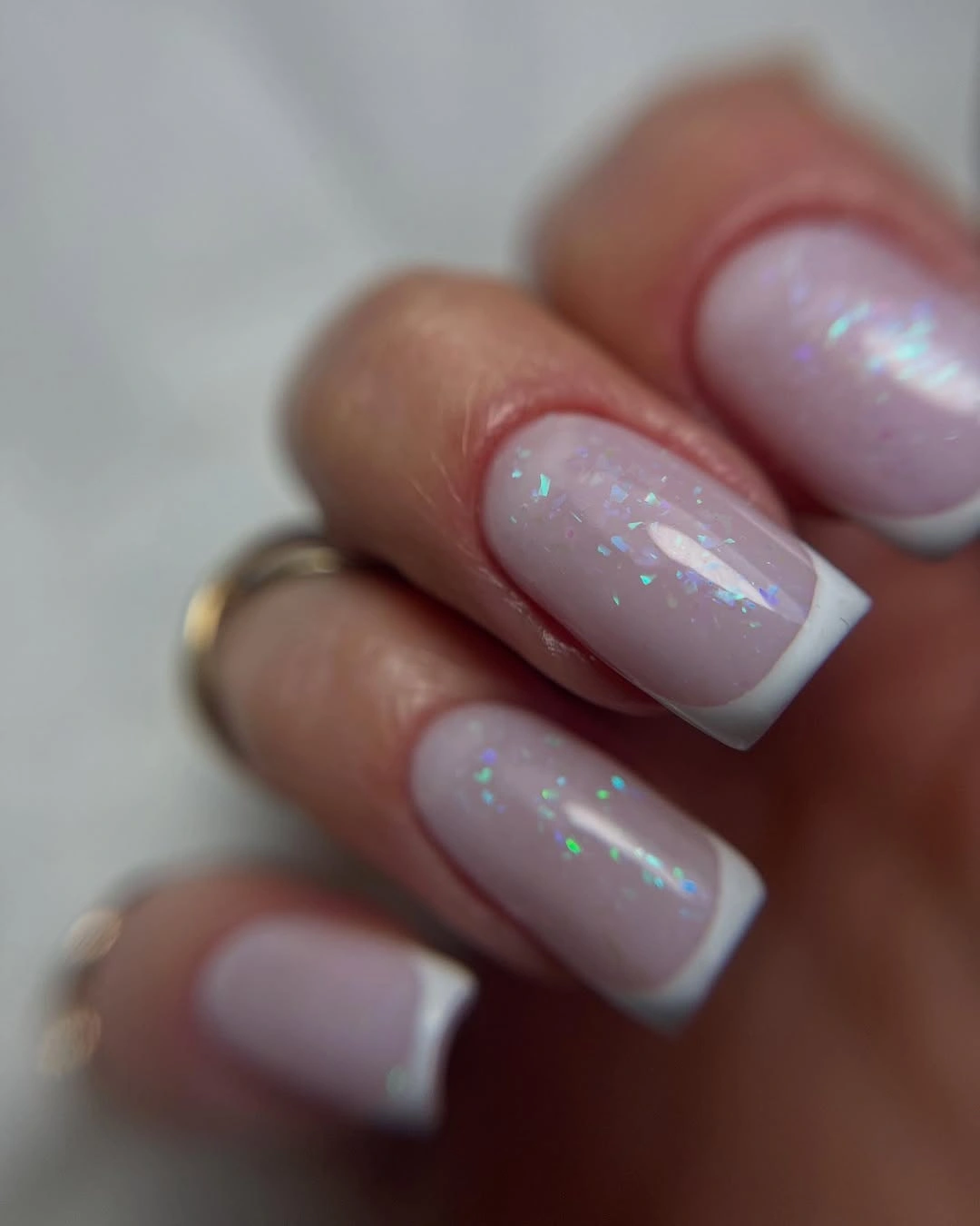 Medium square milky pink French nails with iridescent shimmer