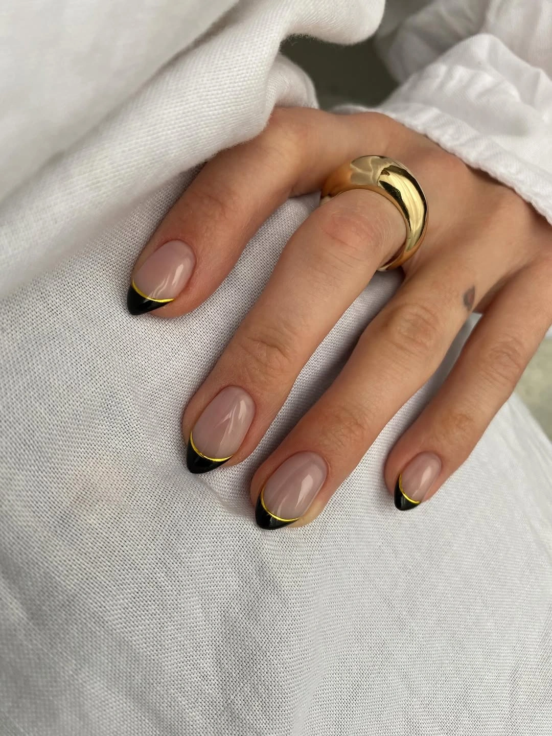 Nude almond nails with black and gold French outlines