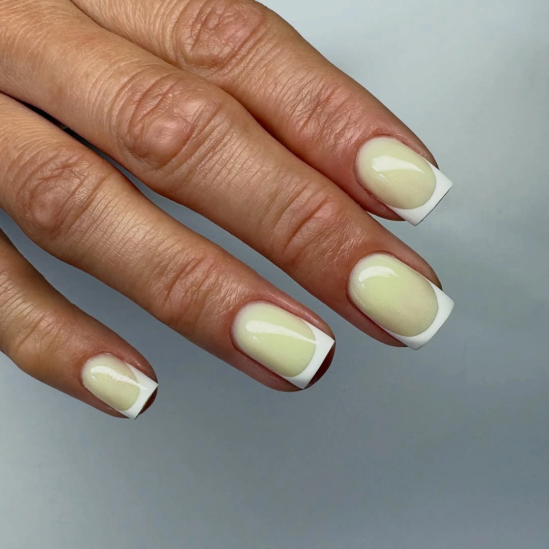 Creamy pale green square nails with crisp white corner tips