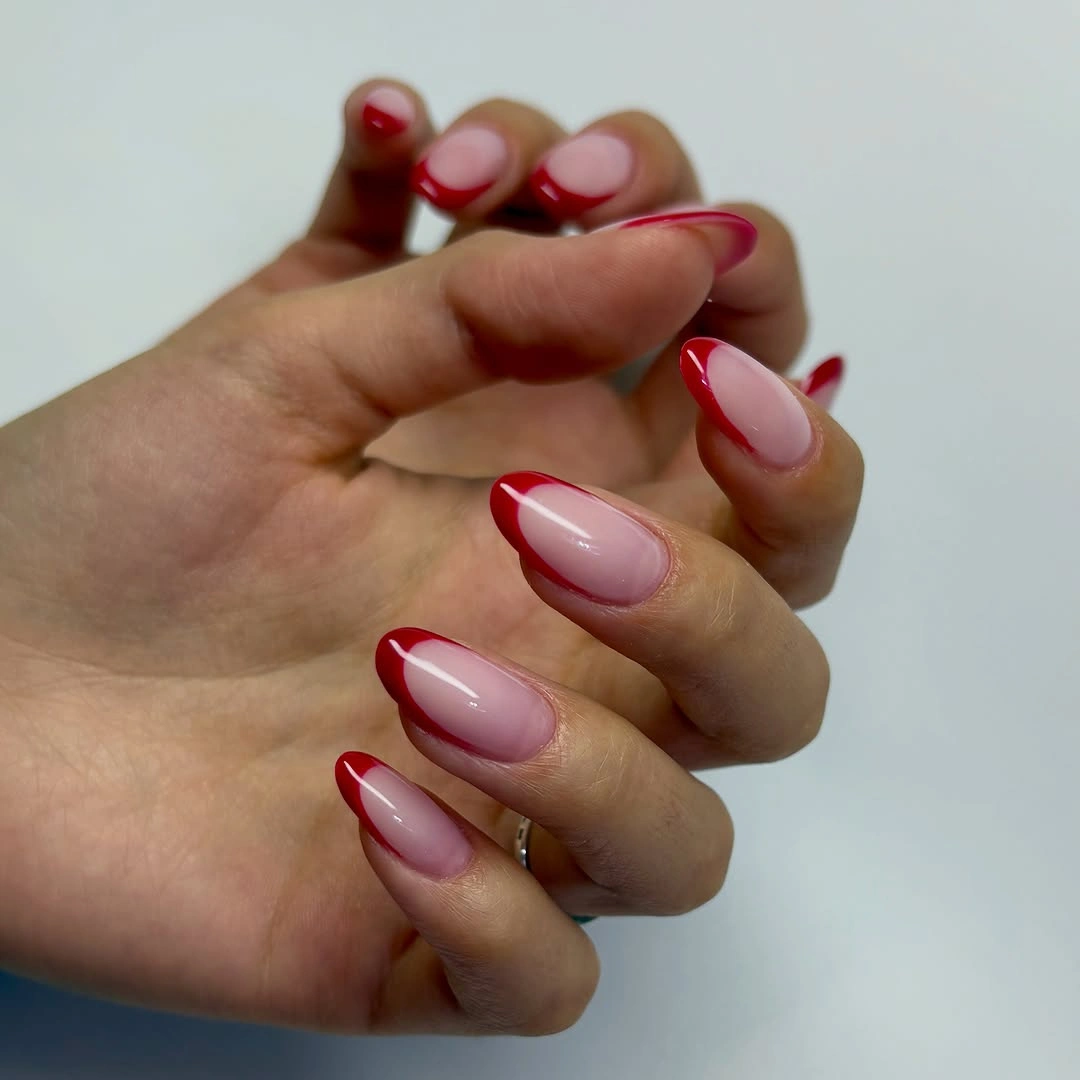Sheer pink oval nails finished with curved saturated red tips