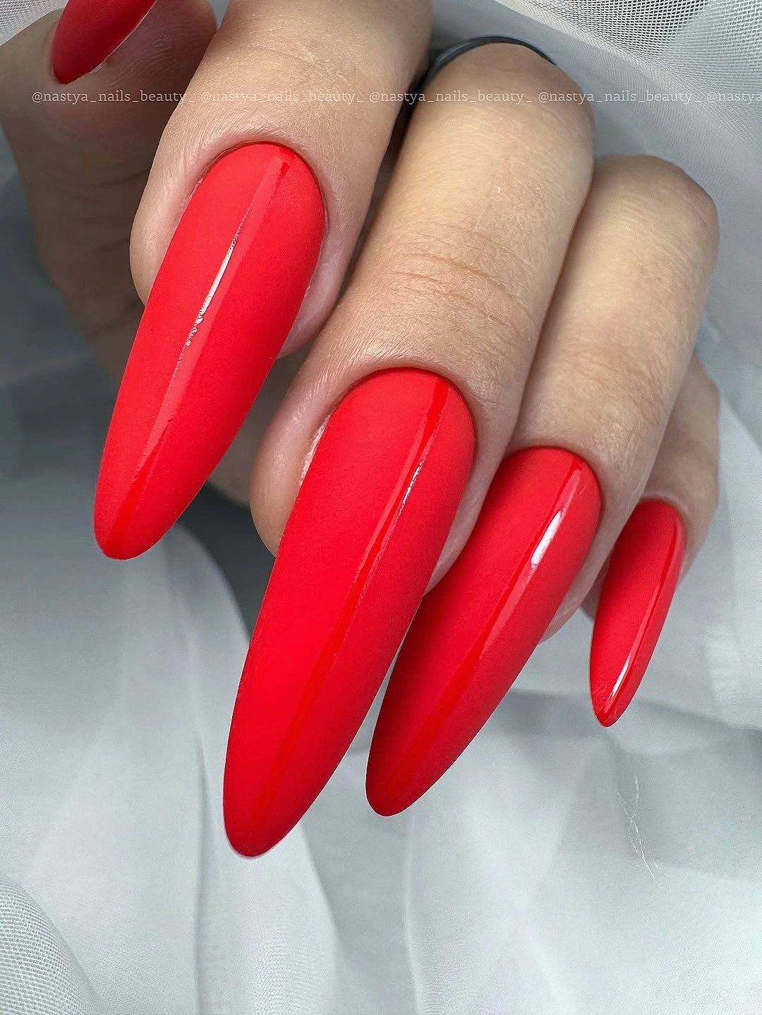 Very long glossy red stiletto nails in a solid color