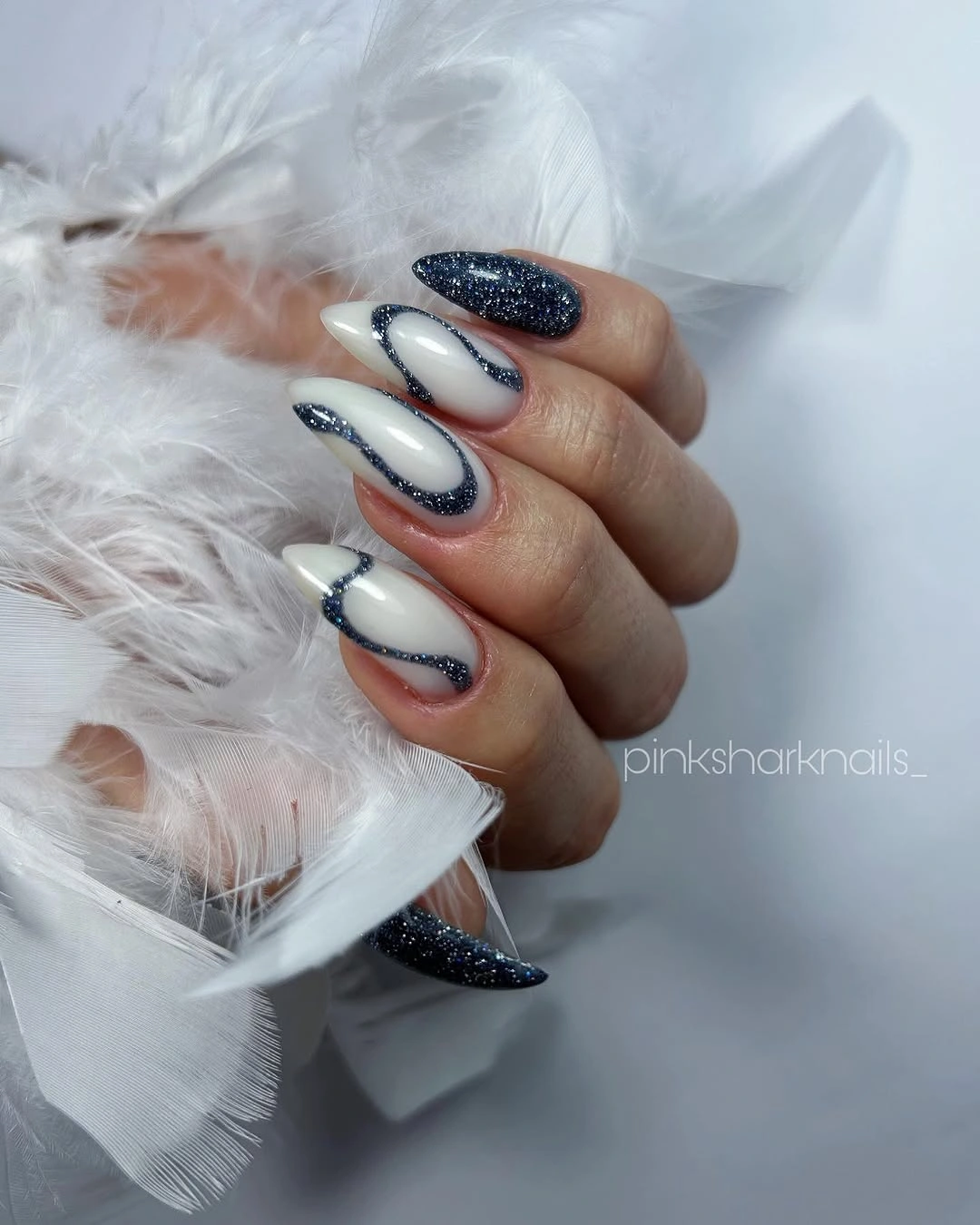 Long milky almond nails with navy curves and glitter tips