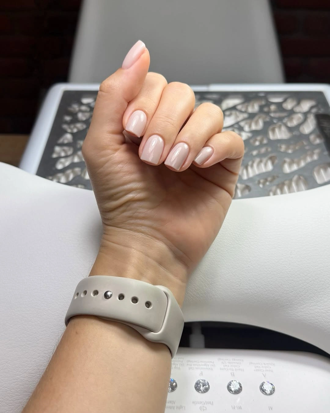 Short pale-pink nails styled with a smartwatch