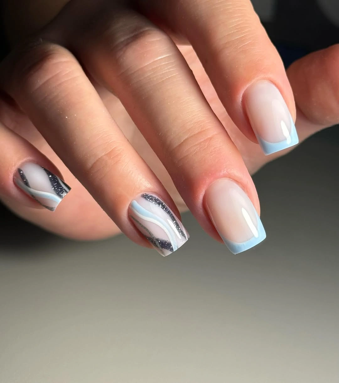 Medium square pale nails with light blue tips and one dark accent