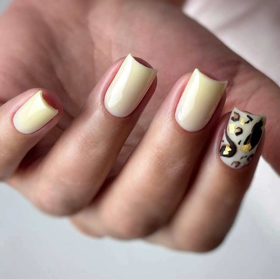 Creamy yellow nails with one black-and-white graphic accent