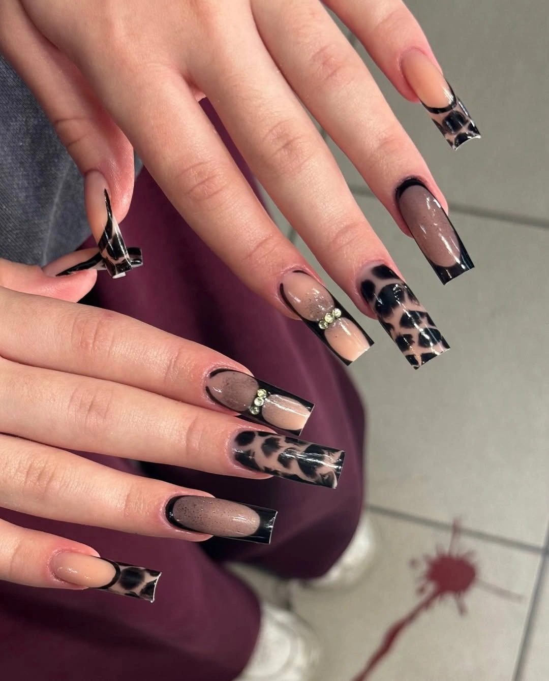 Medium coffin nude nails with black tips and patterned accents