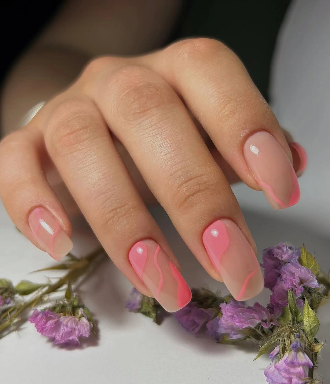 Rounded pink nails with bright curved French-like accents