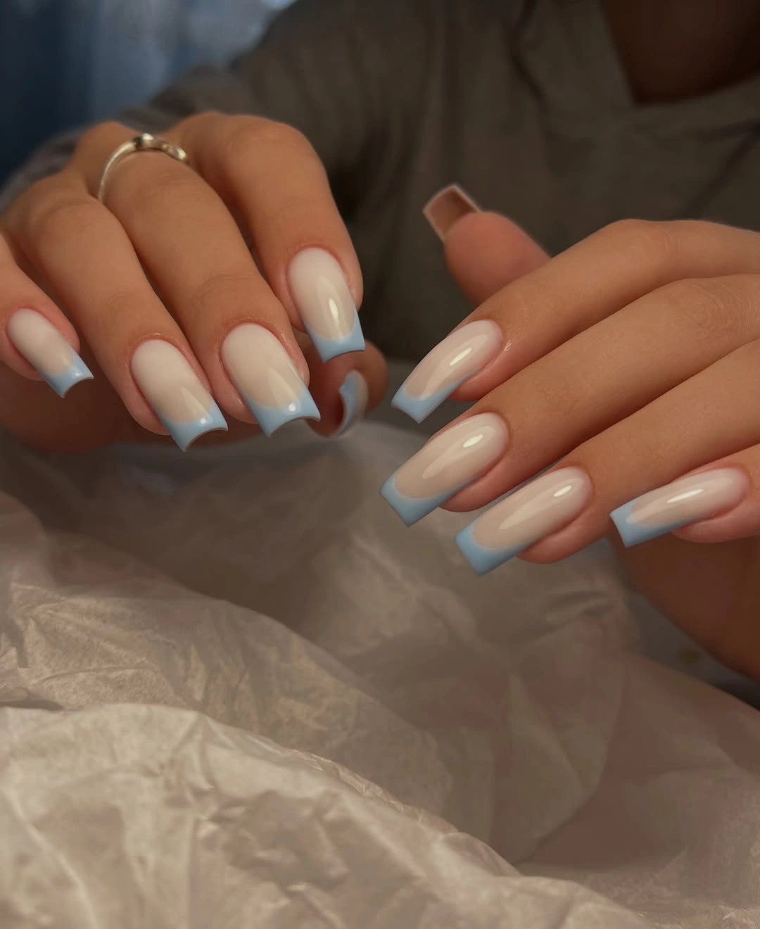 Long square nails with nude bases and pale blue French tips