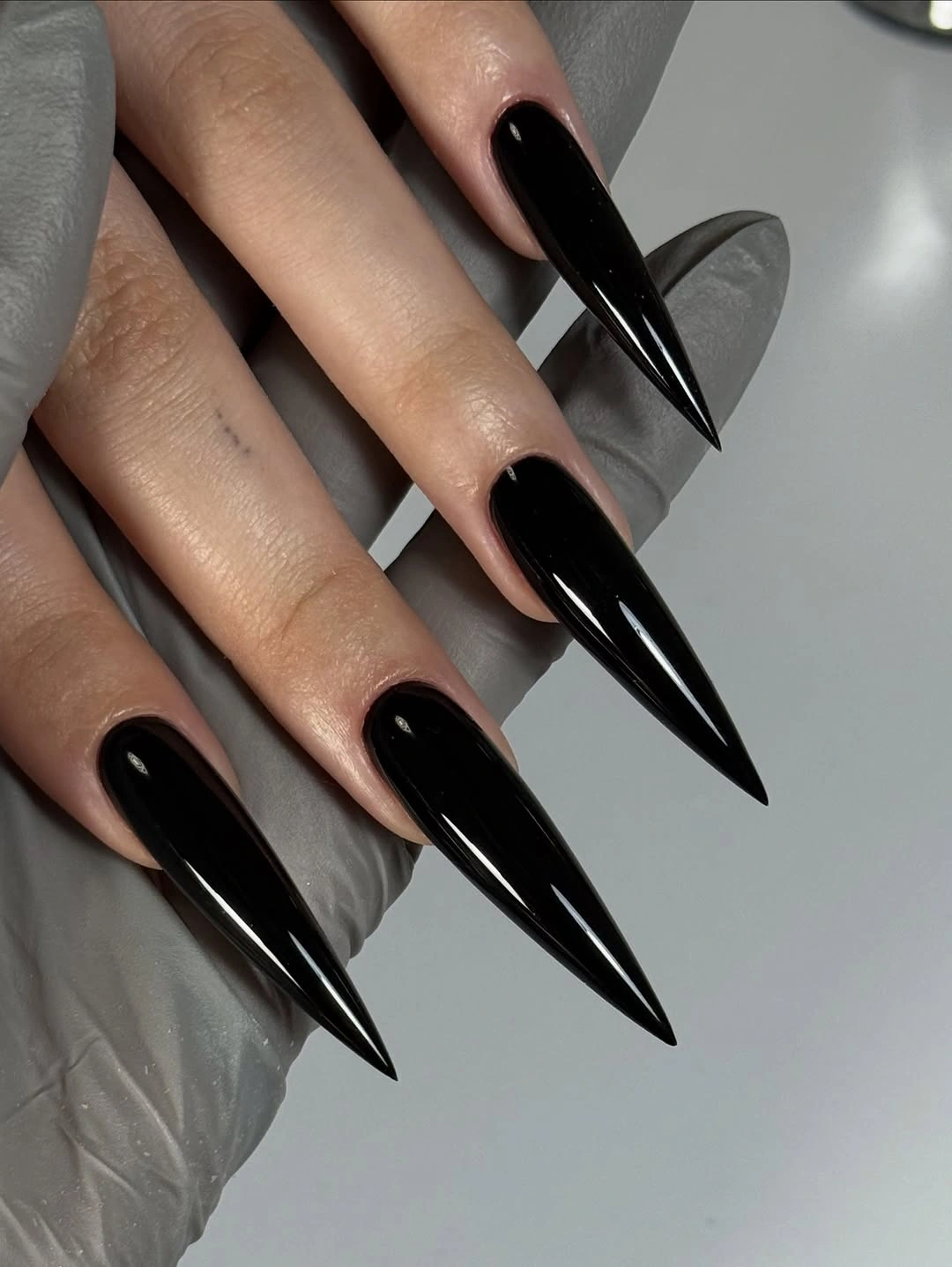 Long high-gloss black stiletto nails with extreme pointed tips