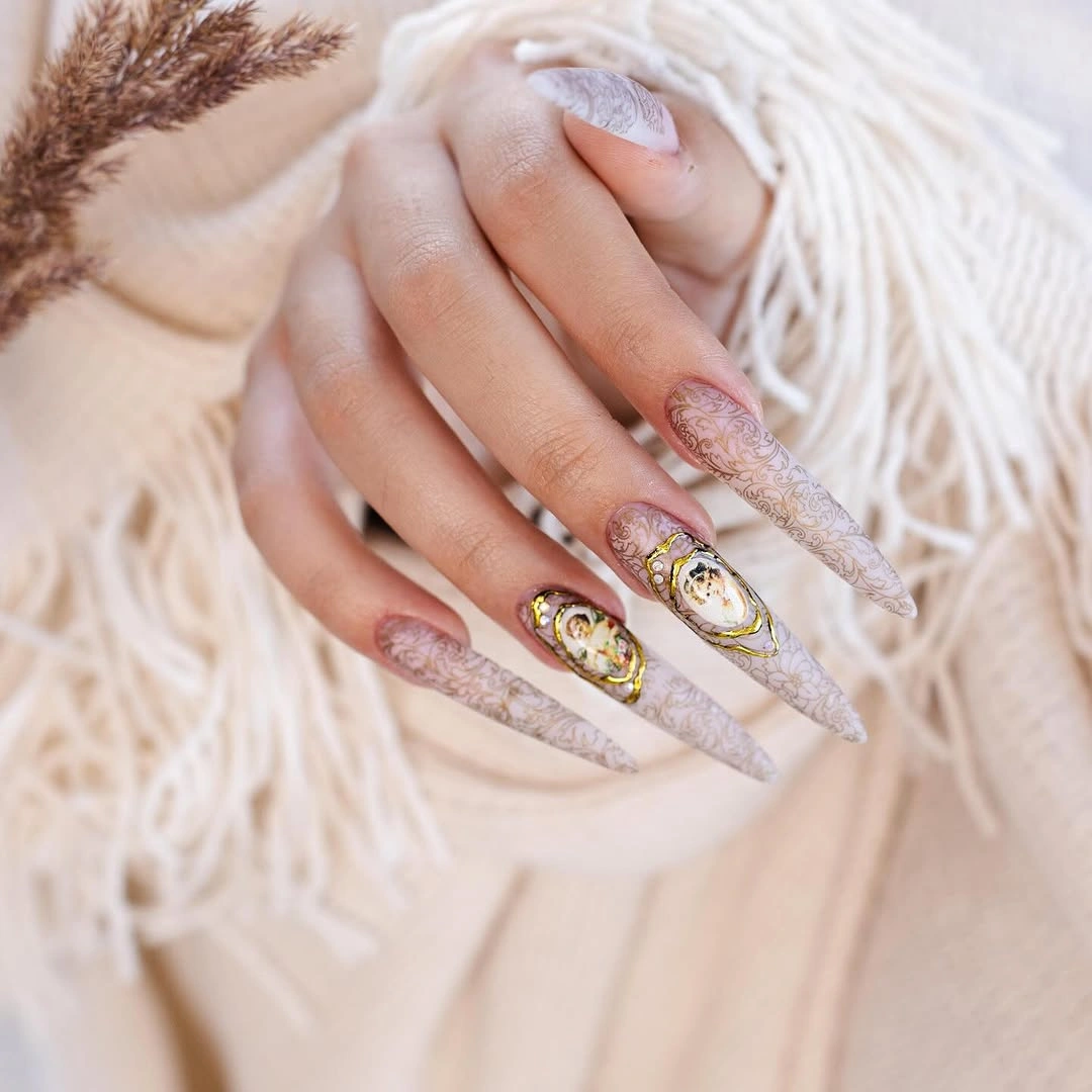 Long pale shimmer stiletto nails with gold floral ornaments