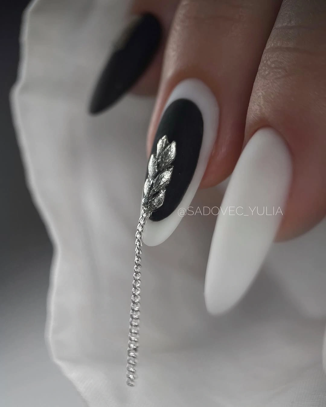 Black and white almond nails with silver leaf and chain detail
