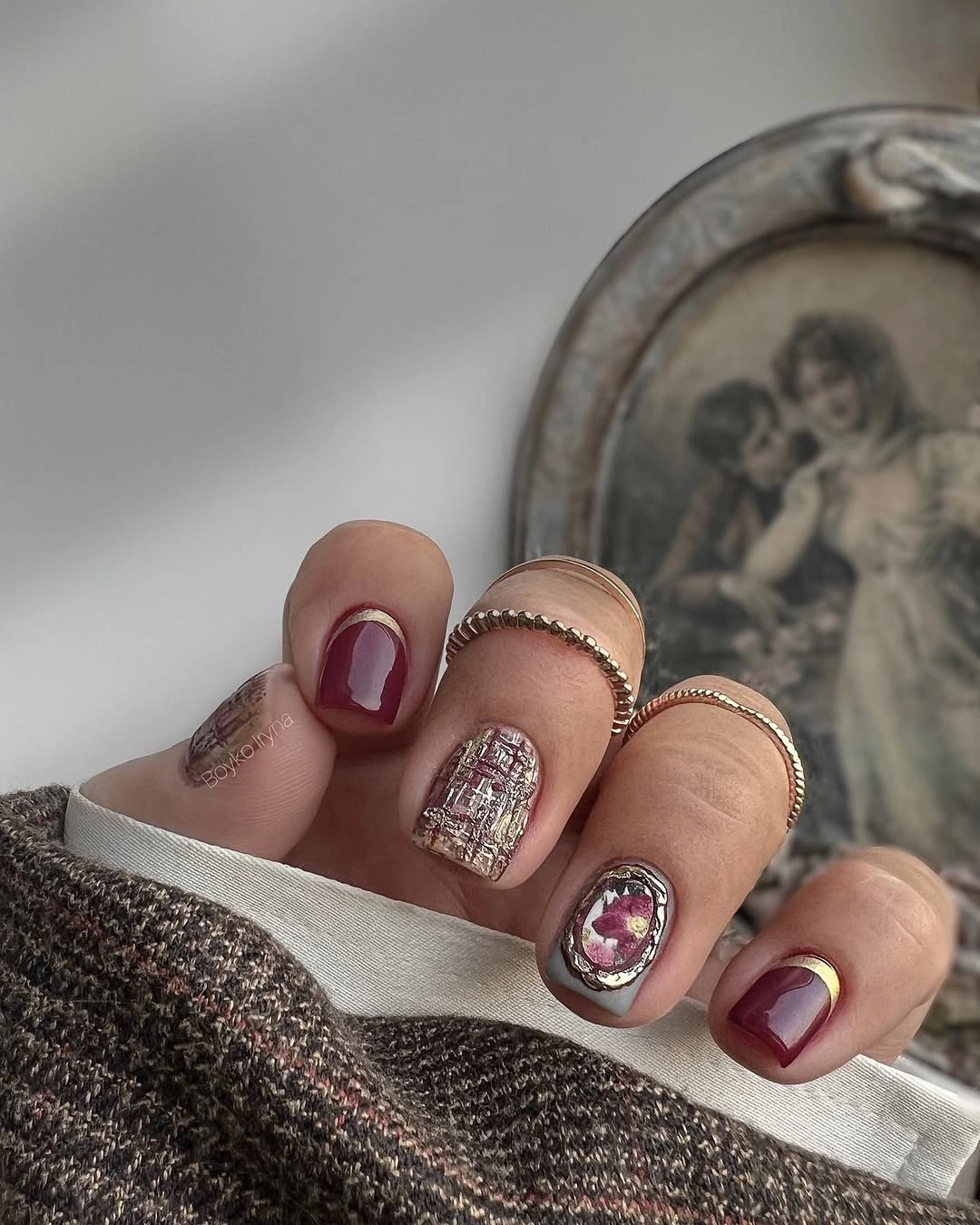 Short burgundy nails with nude metallic ornate accent