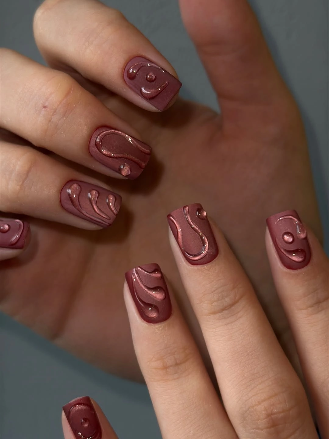 short berry-brown matte nails with rounded tone-on-tone squiggles