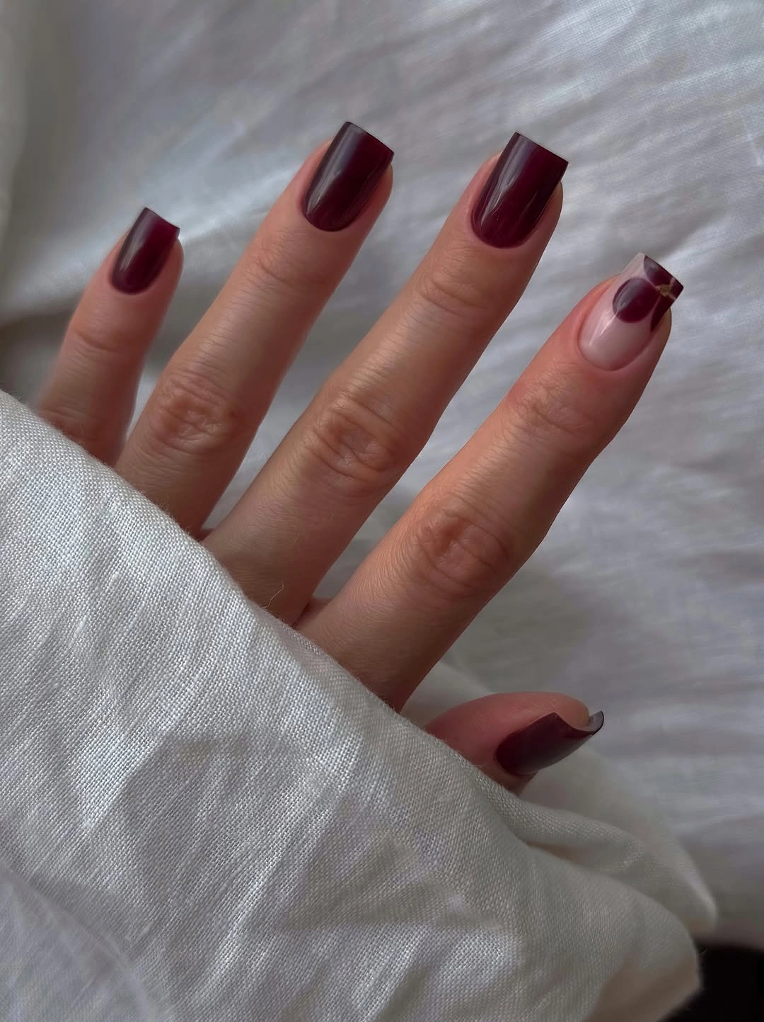 Medium rounded square burgundy nails with one diagonal accent