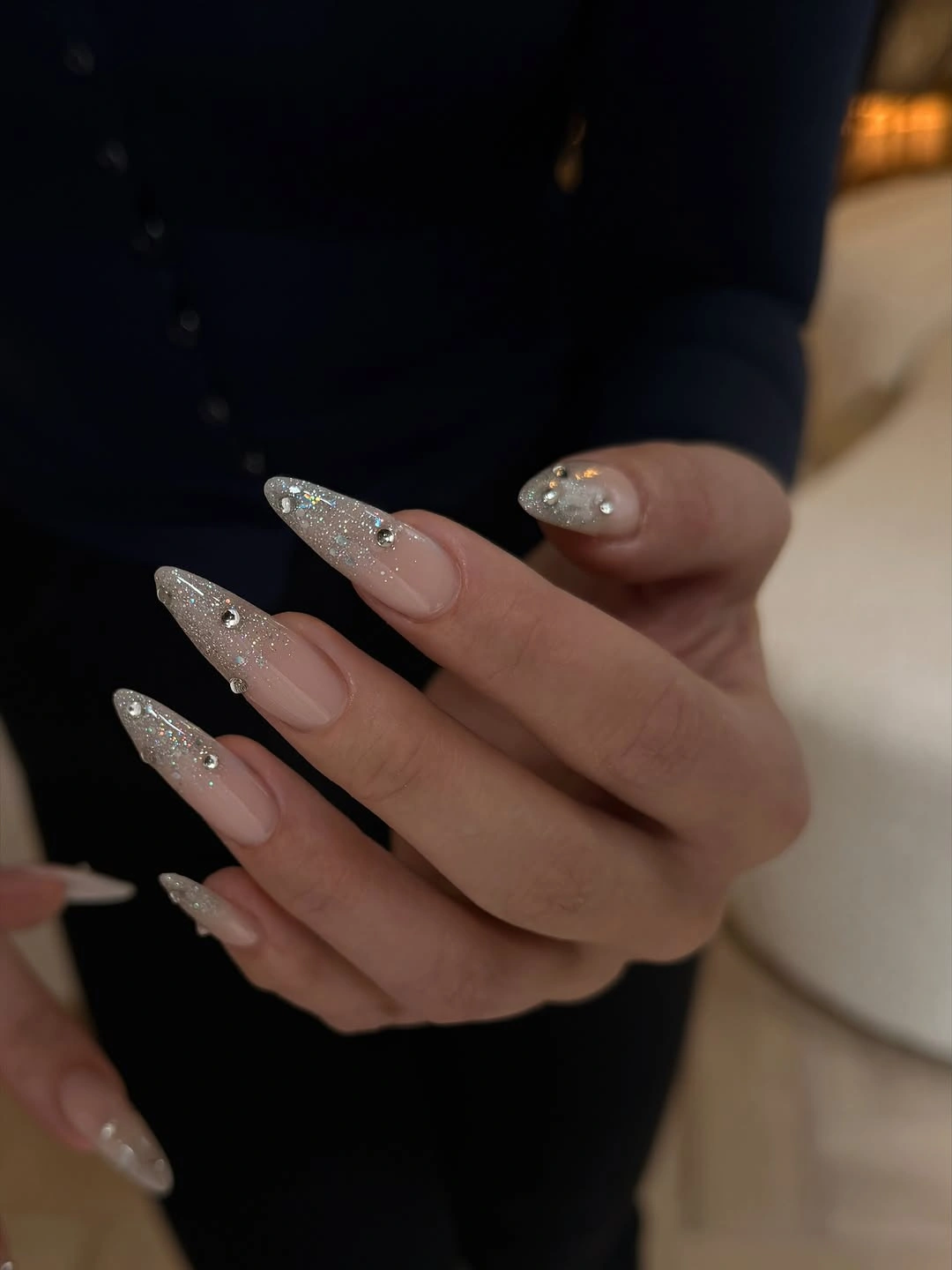 Long almond nude nails with concentrated silver glitter tips