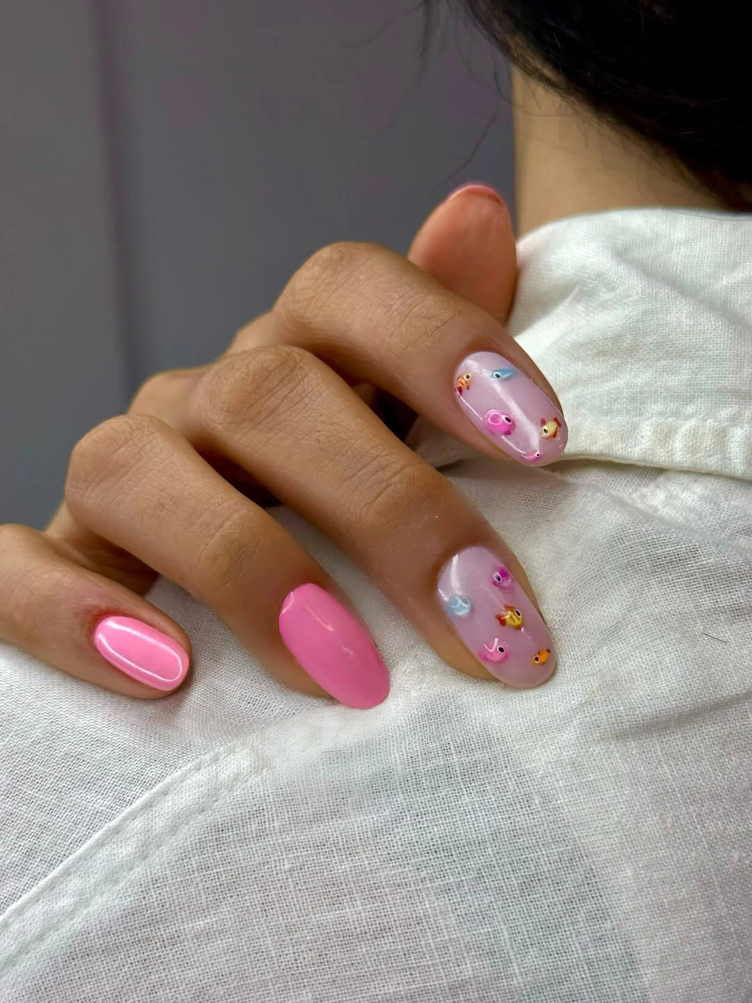 Medium rounded pink nails with tiny pink yellow and blue accents