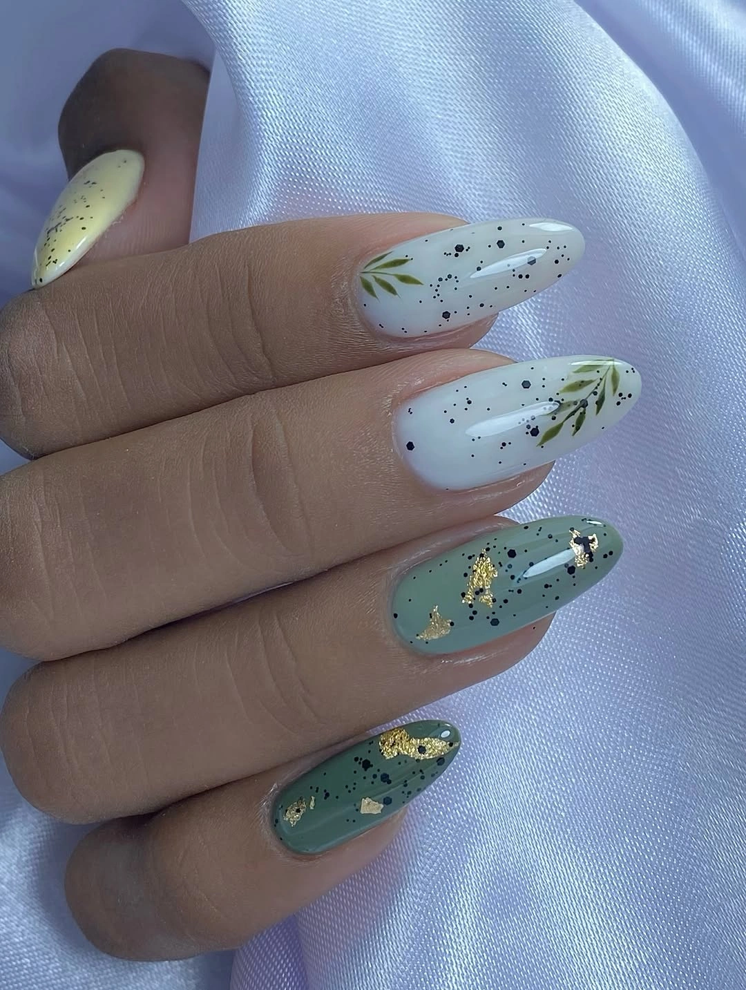 Medium almond pastel nails with botanical lines and gold flecks
