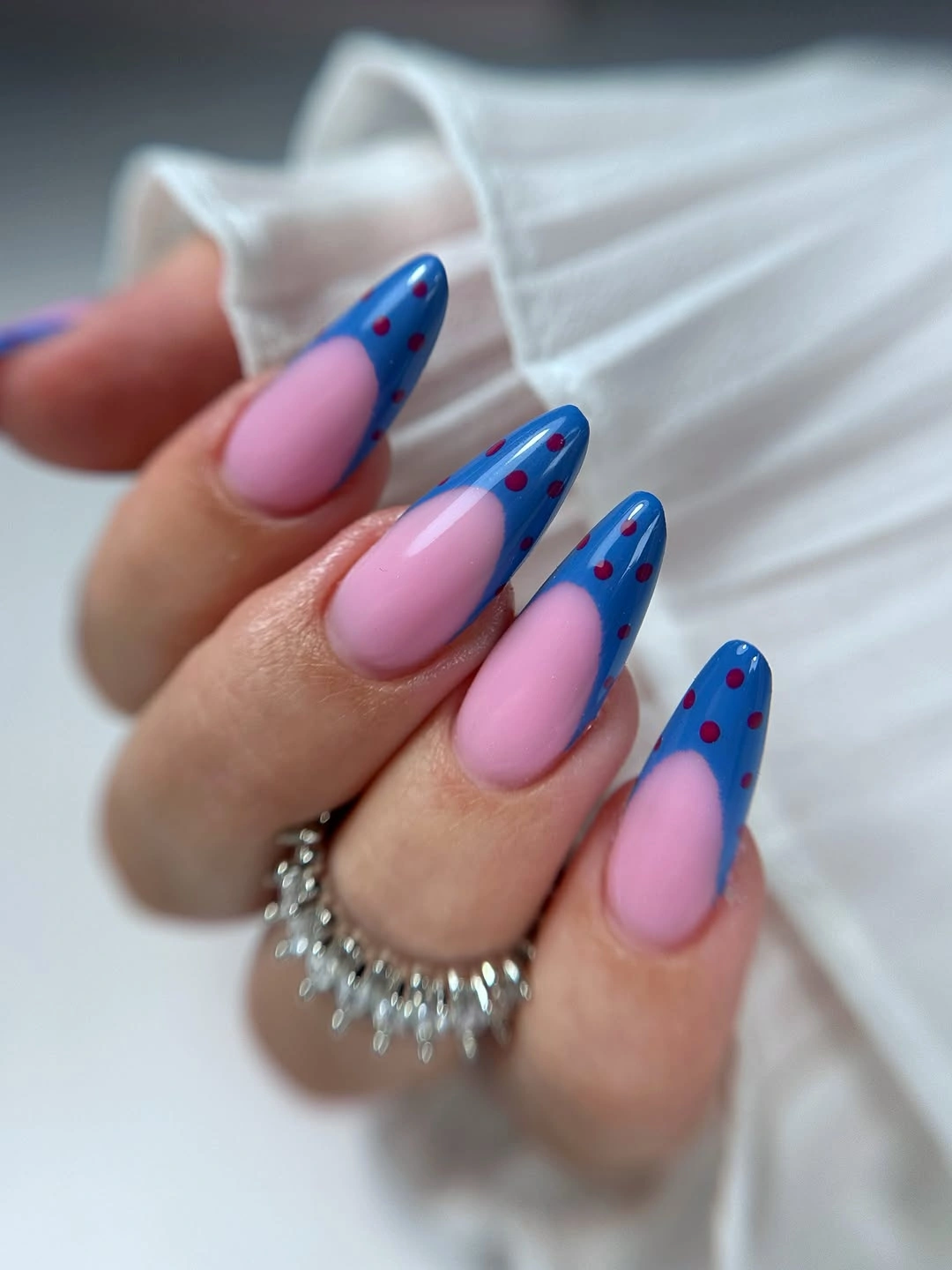 Long almond pink nails with blue panels and red dot accents