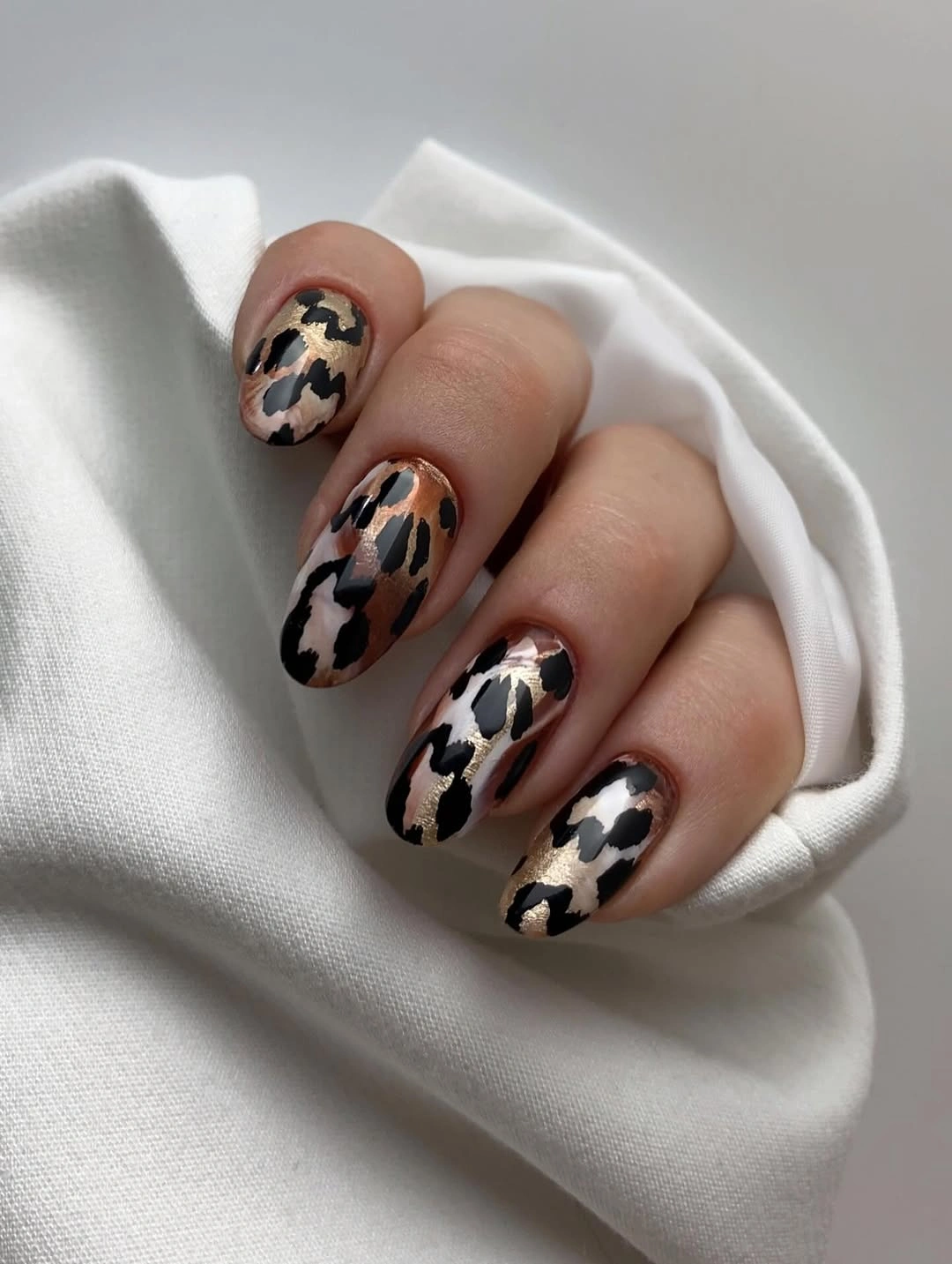 Medium oval cream nails with irregular black brown spotted accents