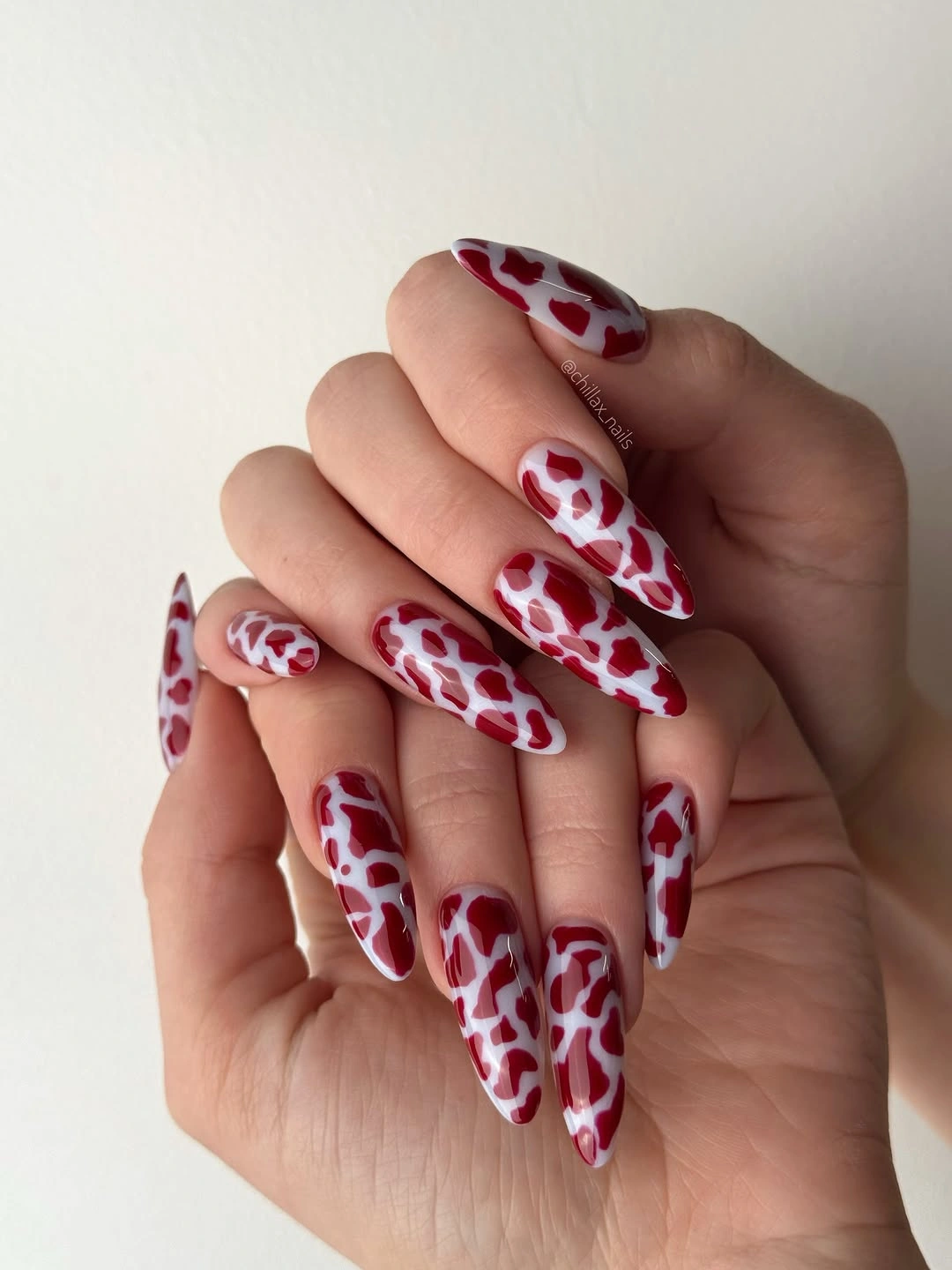 Long stiletto nails covered in a red and white abstract pattern
