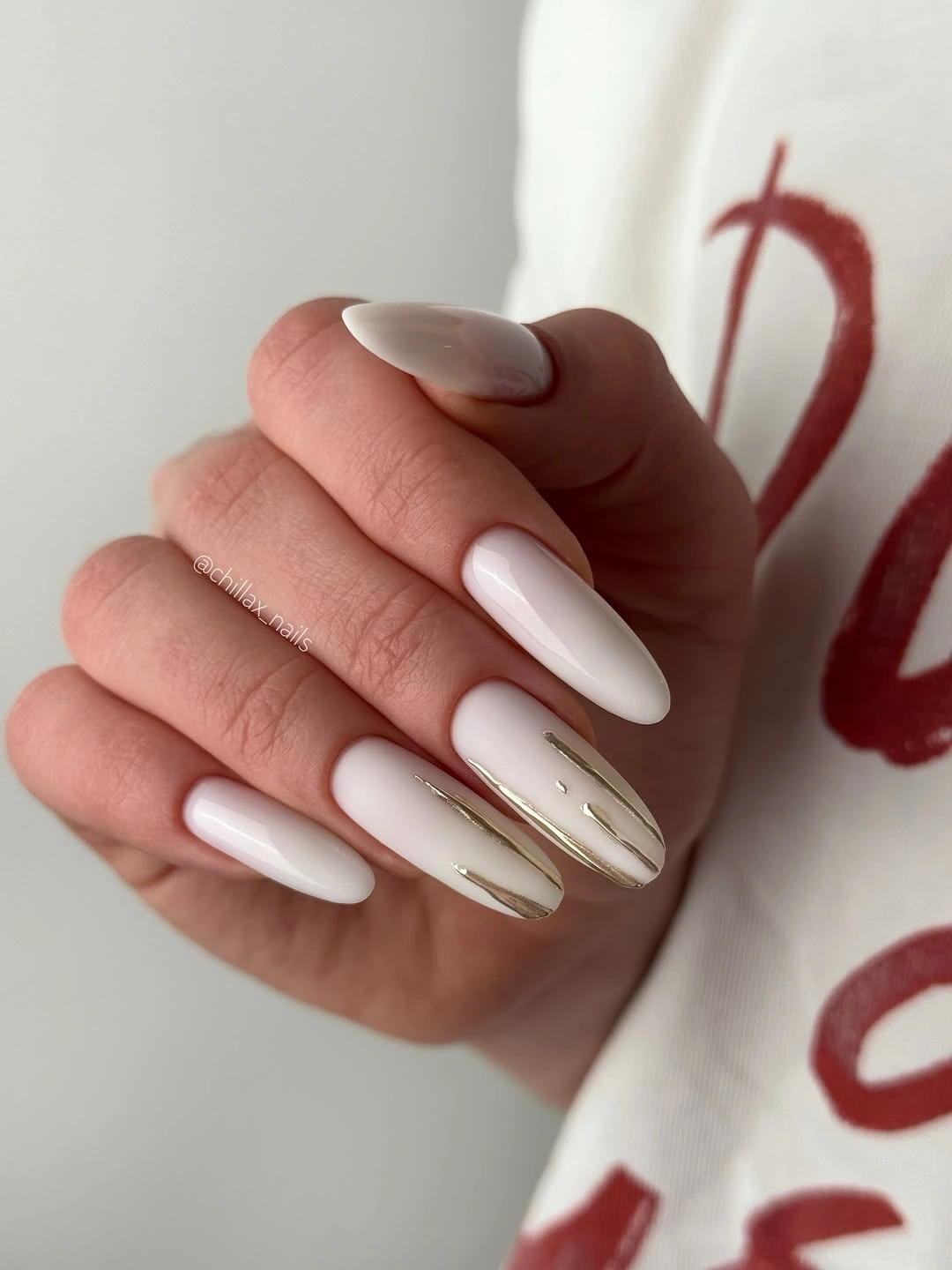 Long white almond nails with slim gold tracing