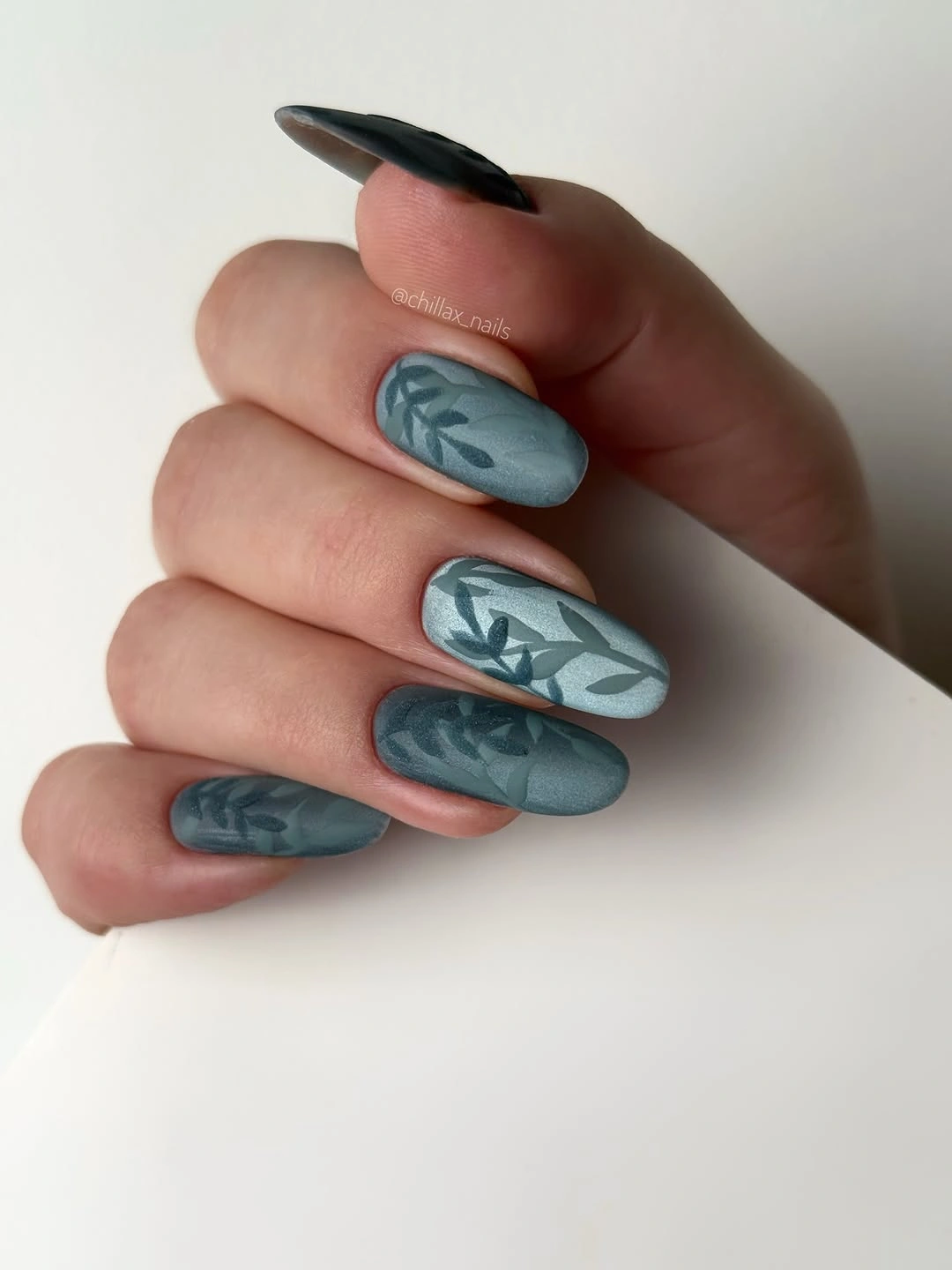 Long teal almond nails with pale botanical line art