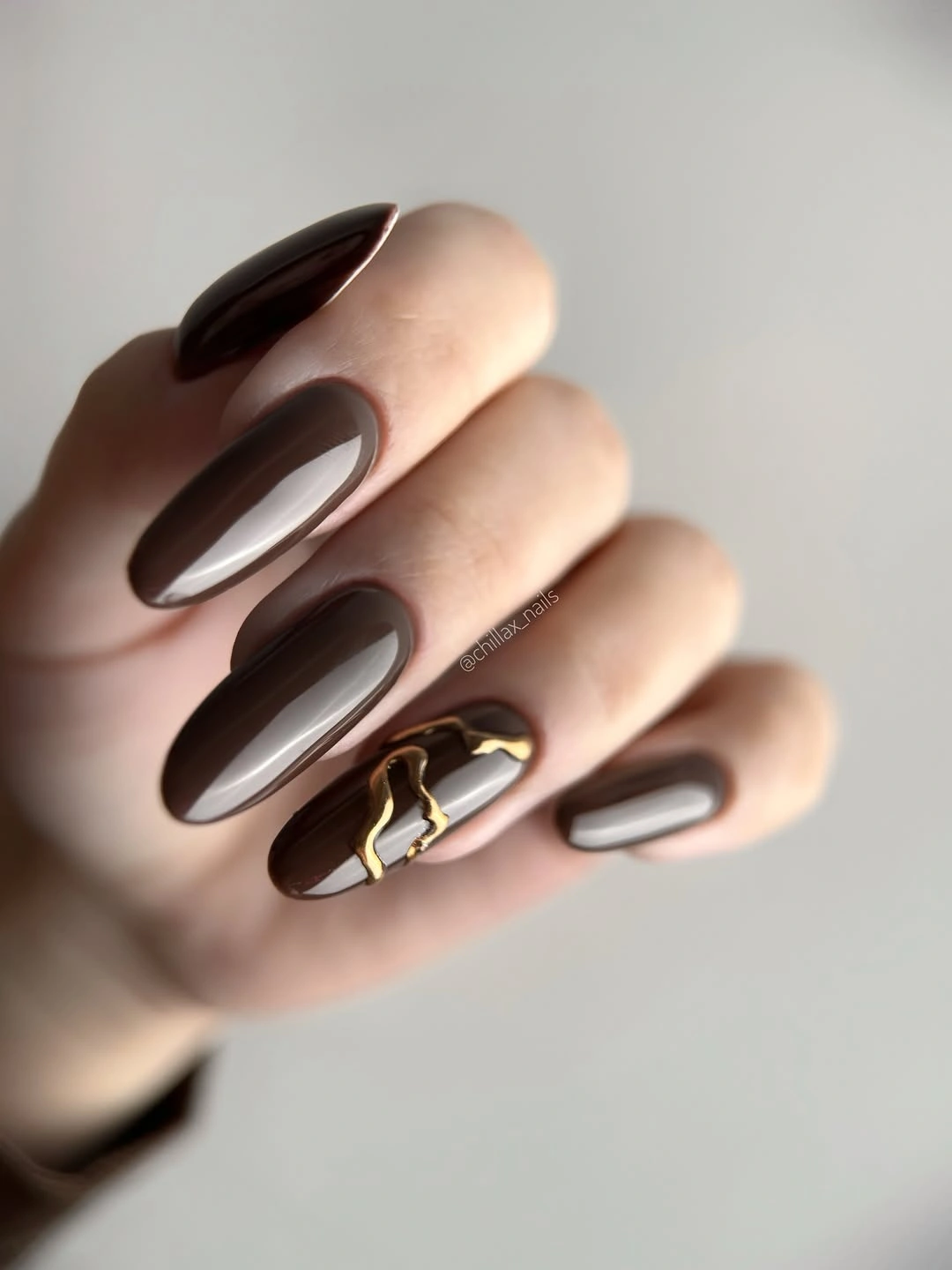 Long brown almond nails with one beige metallic accent