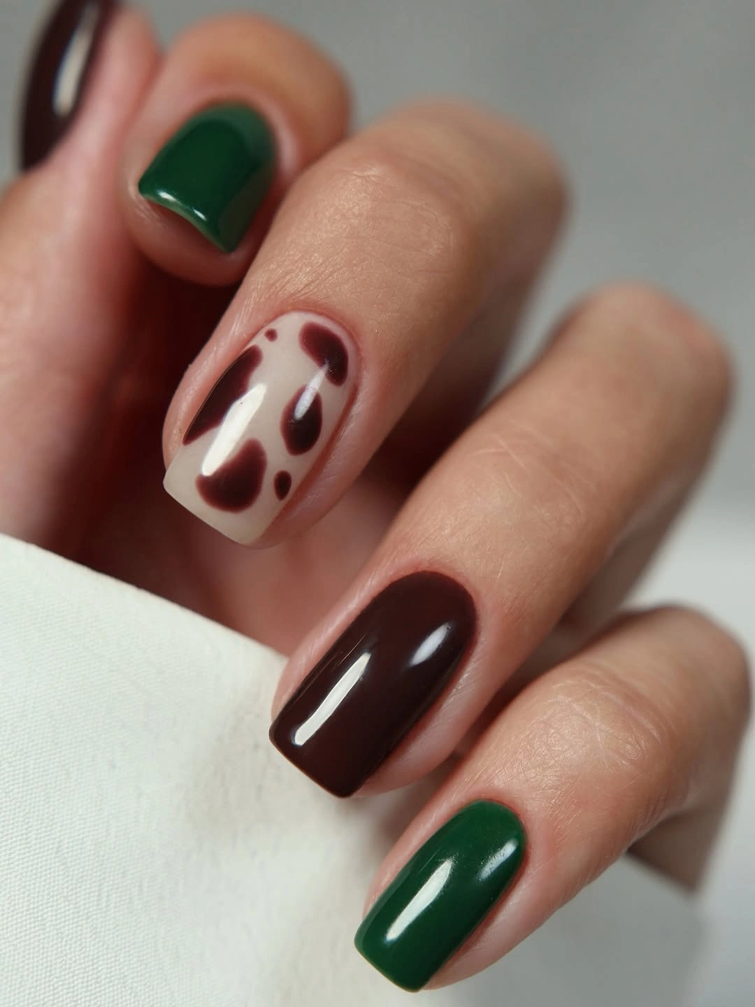 Short square nails mixing forest green burgundy and cream abstract accents