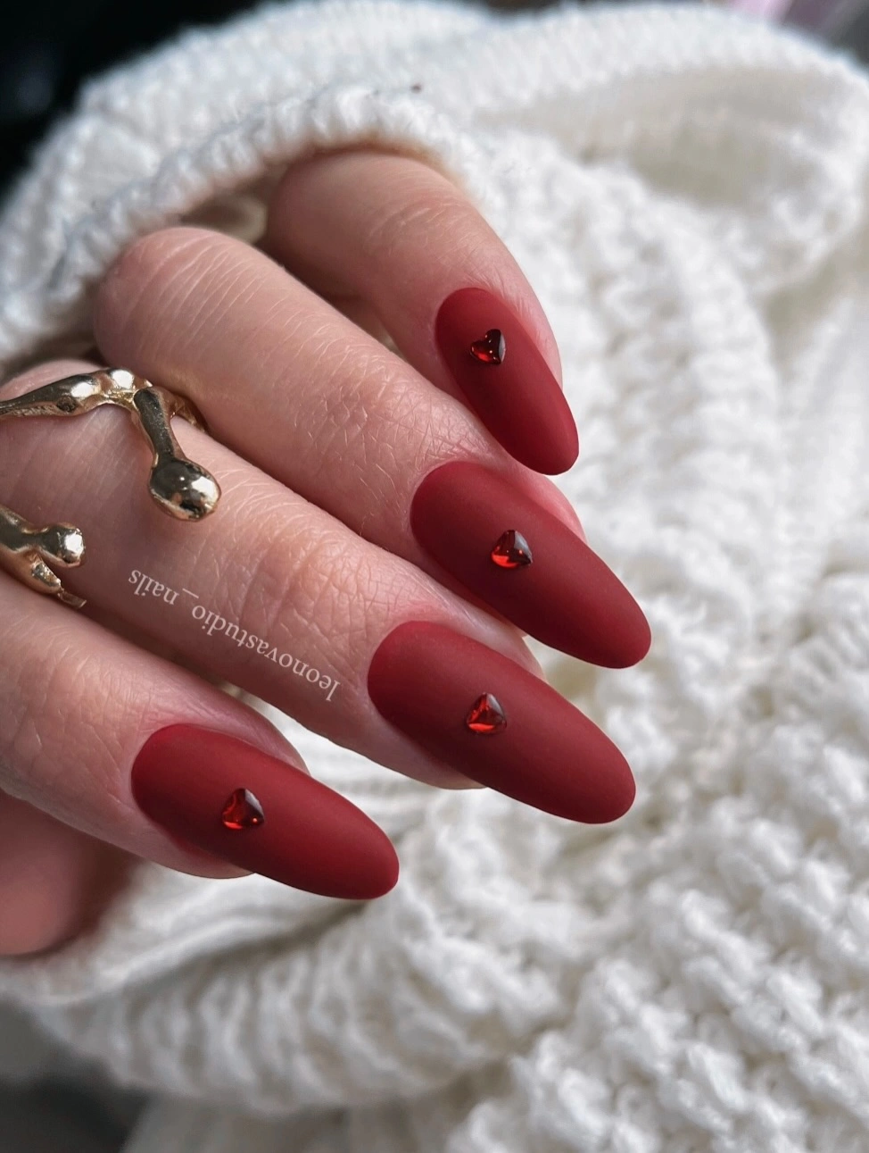 Long matte red almond nails with one small jewel on each nail