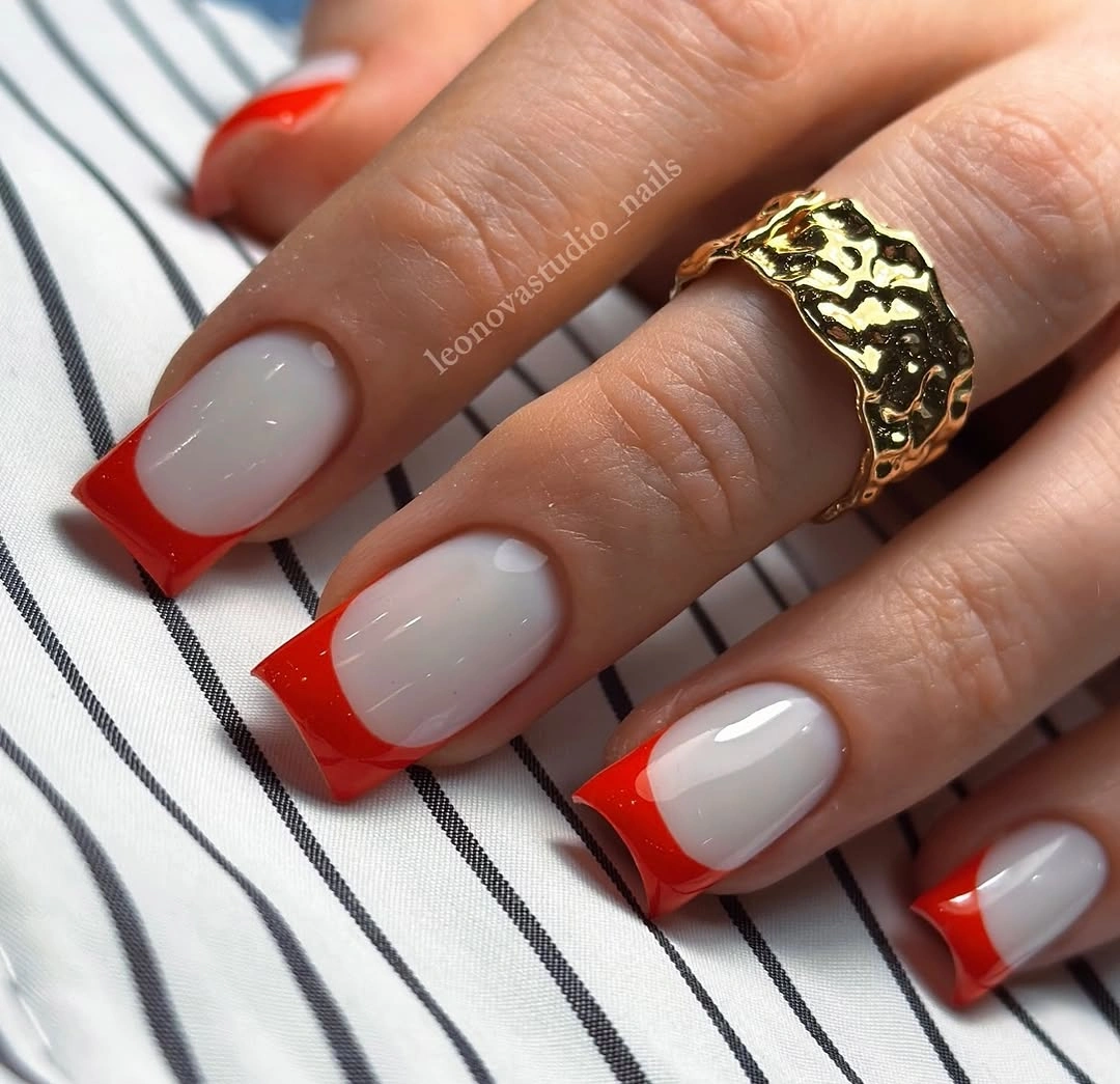 Short square nails with milky bases and vivid red French tips