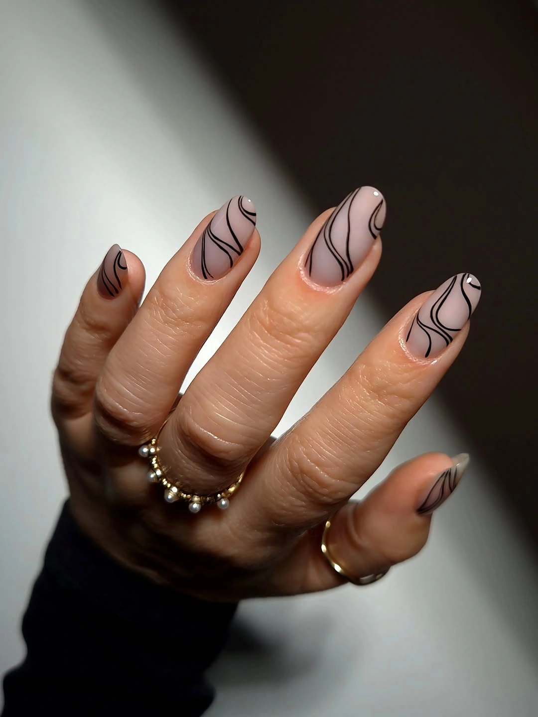 Nude almond nails with thin black flowing curves and open space