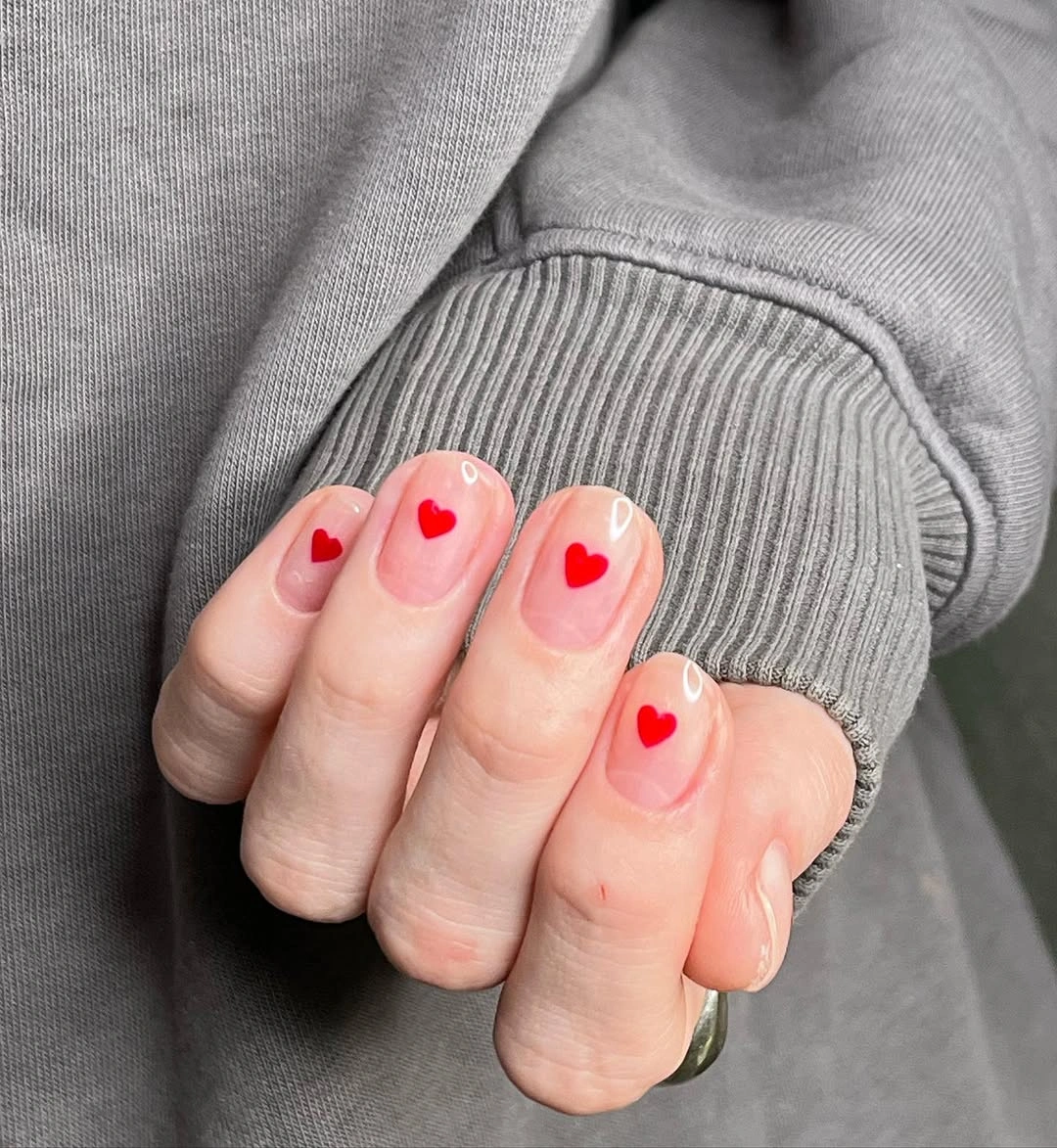 Sheer pink short nails with tiny bright red heart accents