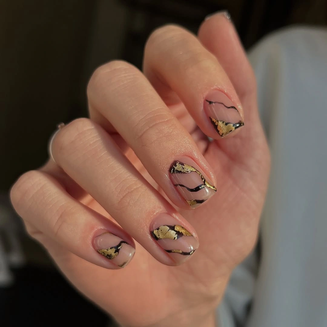 Short nude nails with black and gold veining