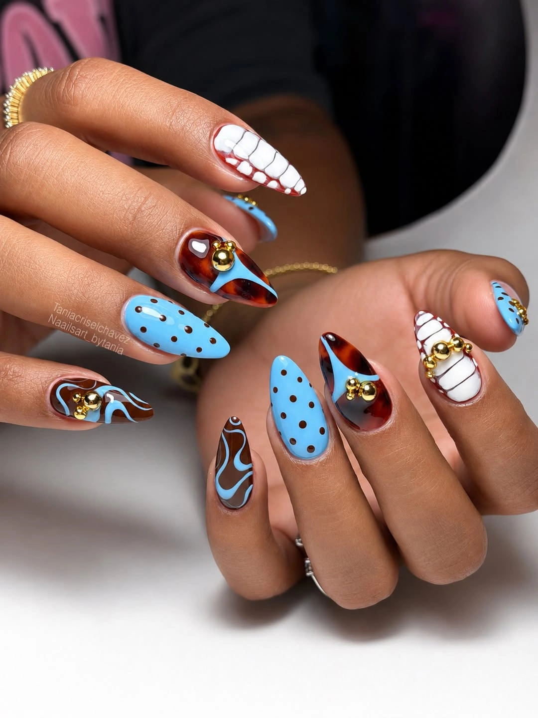 Blue and brown patterned nails with gold bead accents