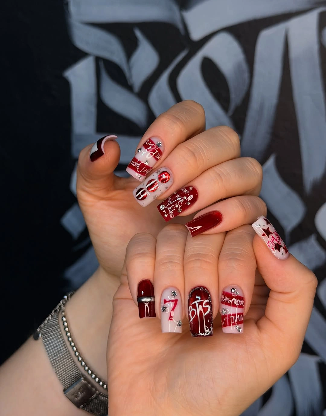 Burgundy square nails with white lettering and stones