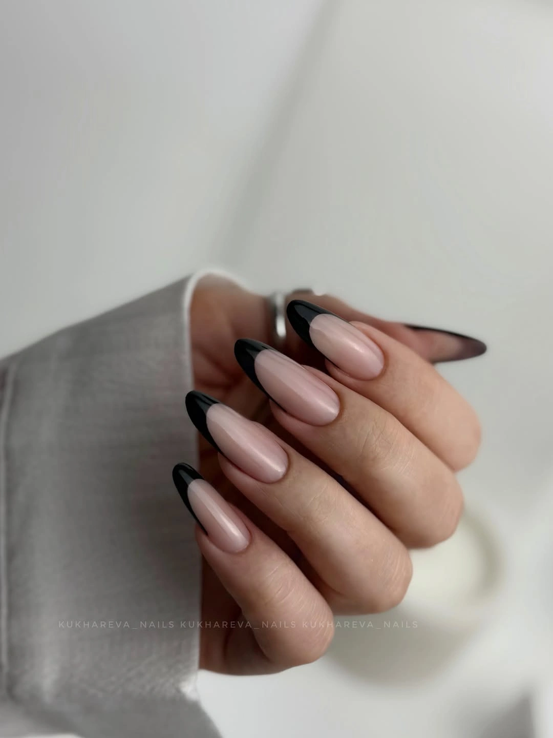 Long almond nails with black French edges over sheer nude