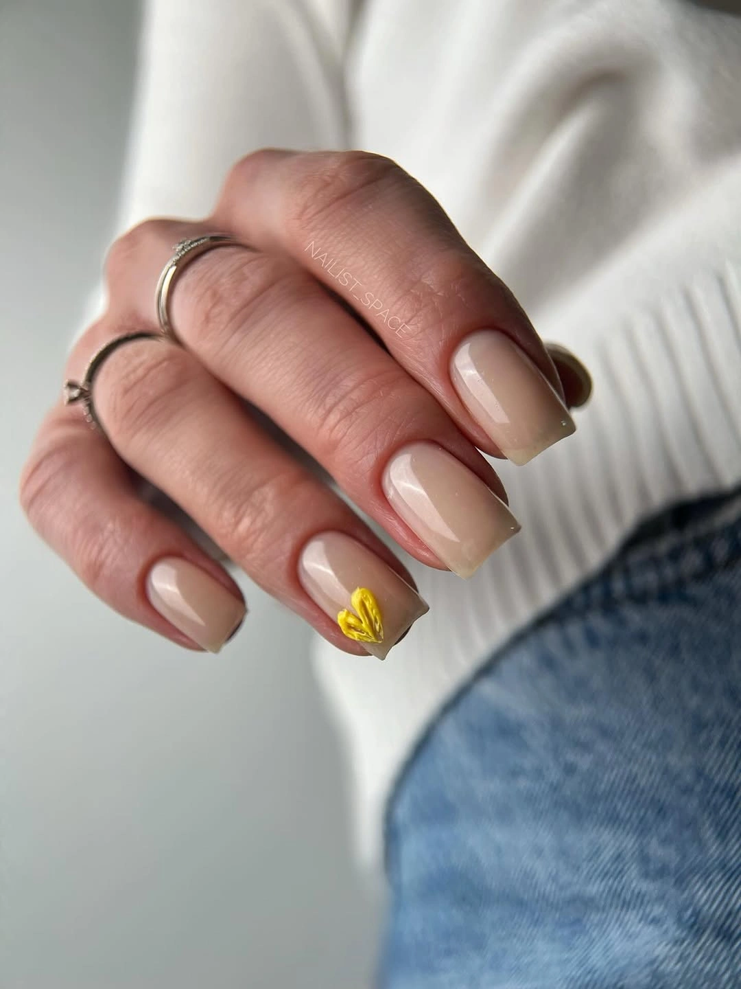medium squoval nude nails with one yellow floral accent