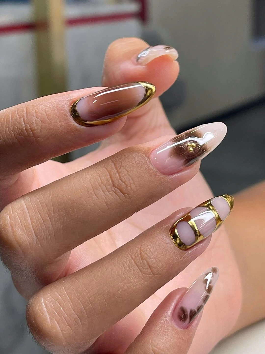 Sheer pink almond nails with dark metallic contour lines