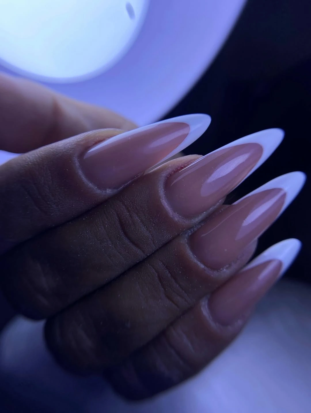 Long pale mauve almond nails under cool colored light