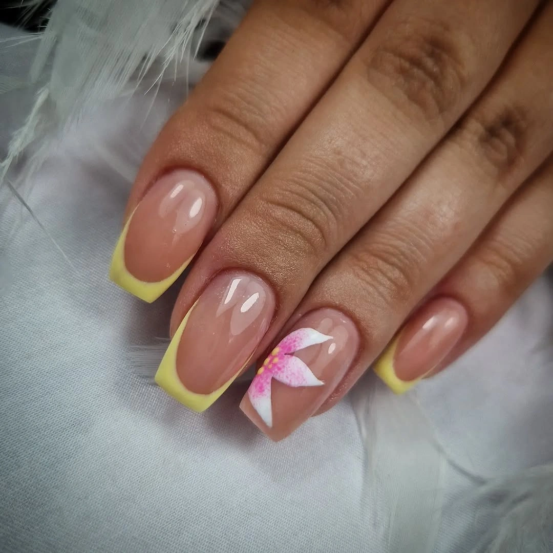 Nude rounded nails with yellow French tips and one flower