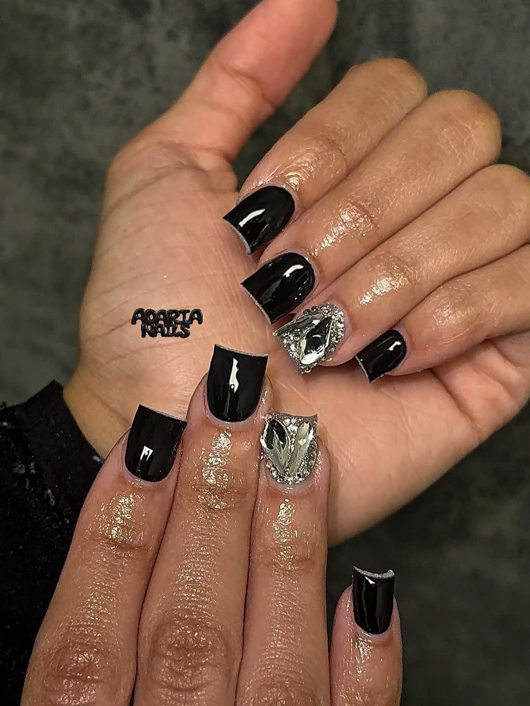 Short glossy black nails with one bright silver accent