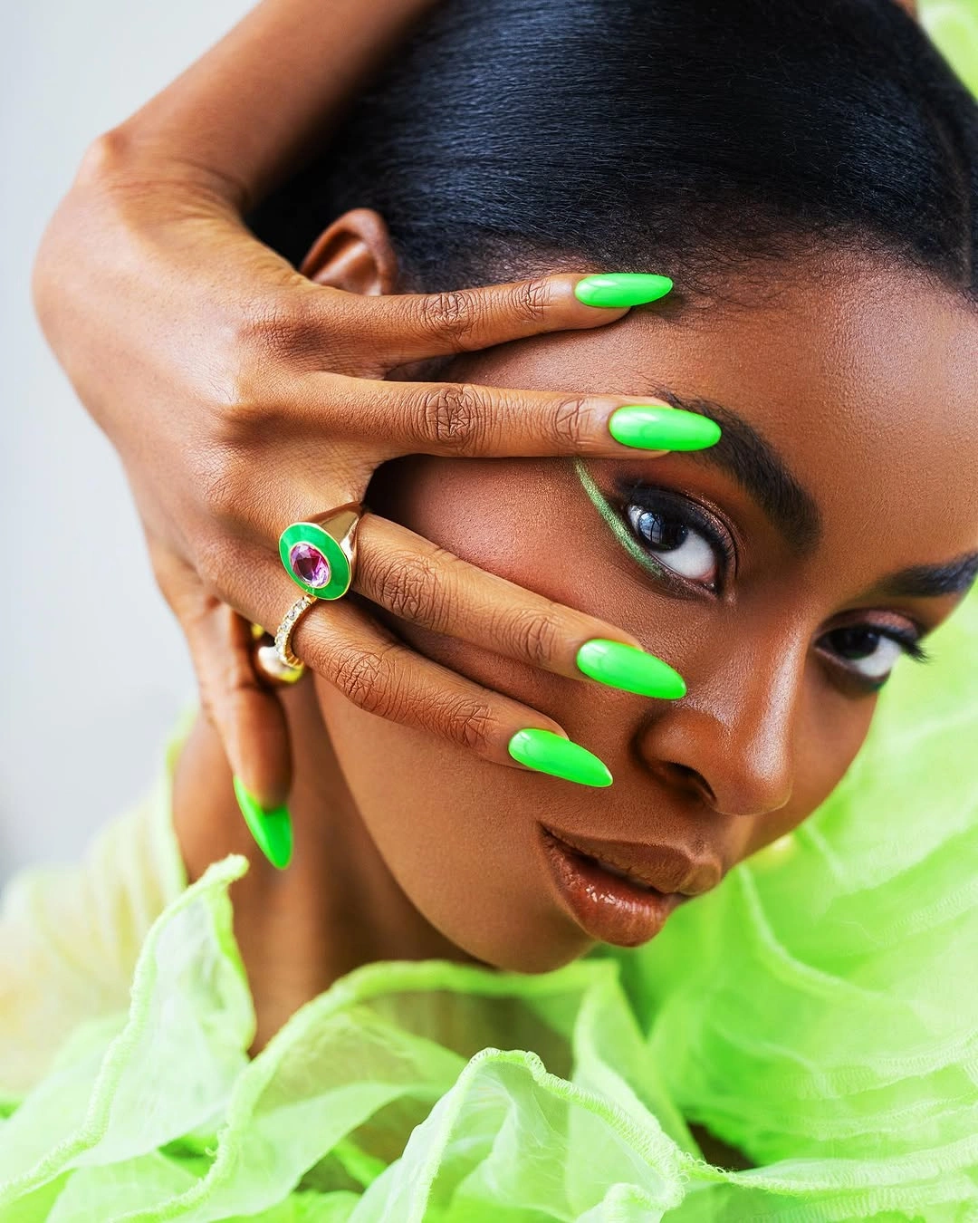Long vivid green pointed nails against lime clothing