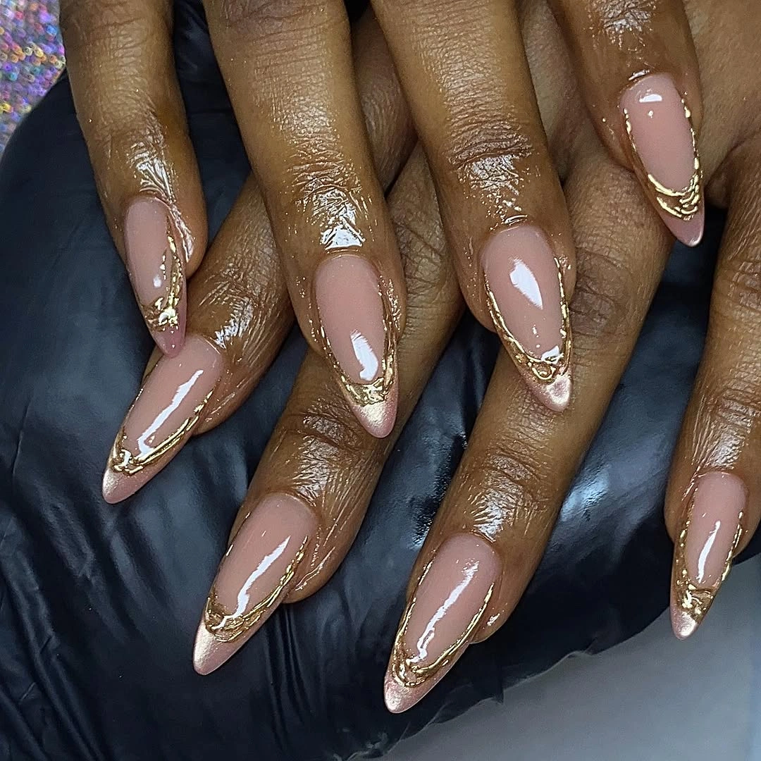 Long nude almond nails with warm metallic edging