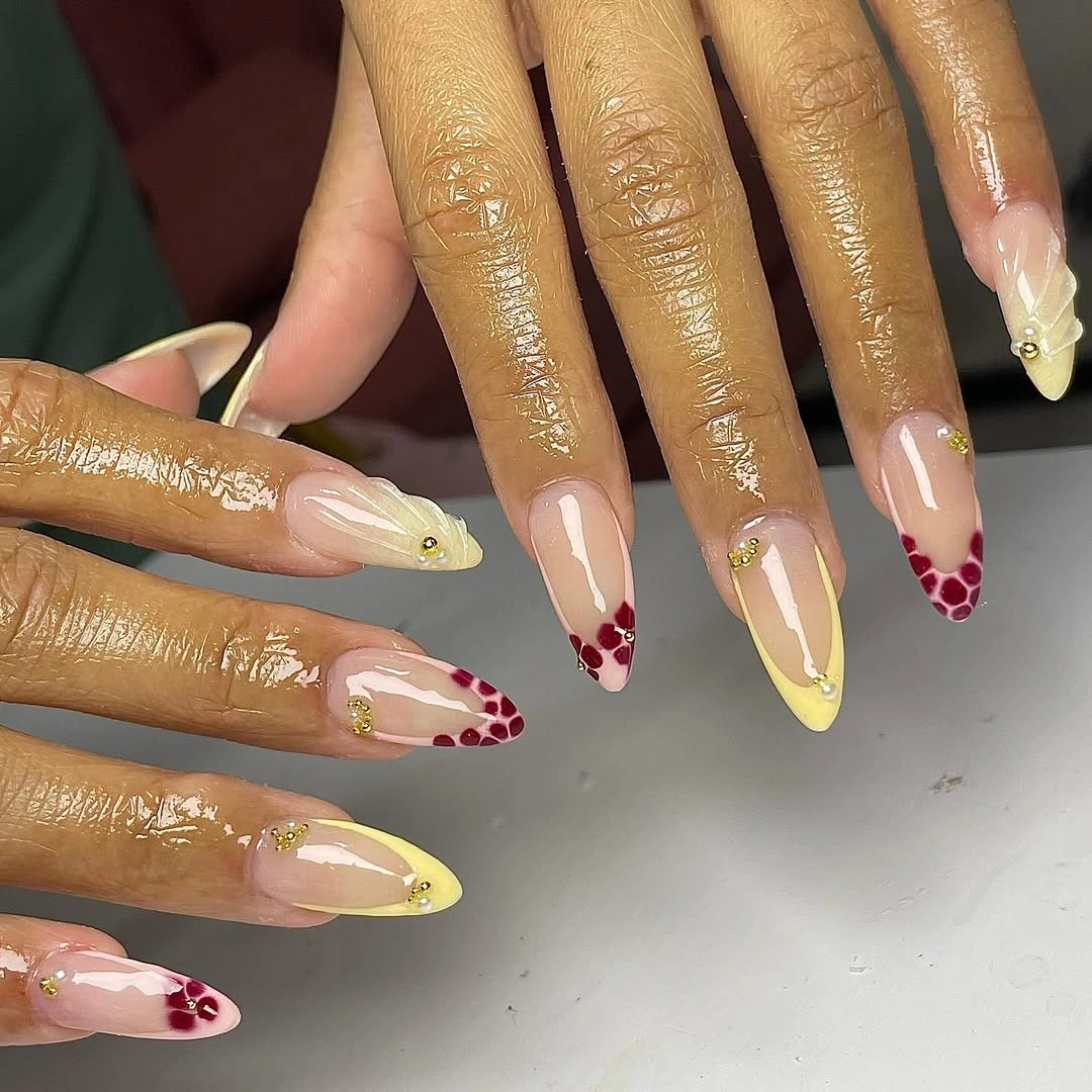 Long almond nails with yellow tips and burgundy patterned accents