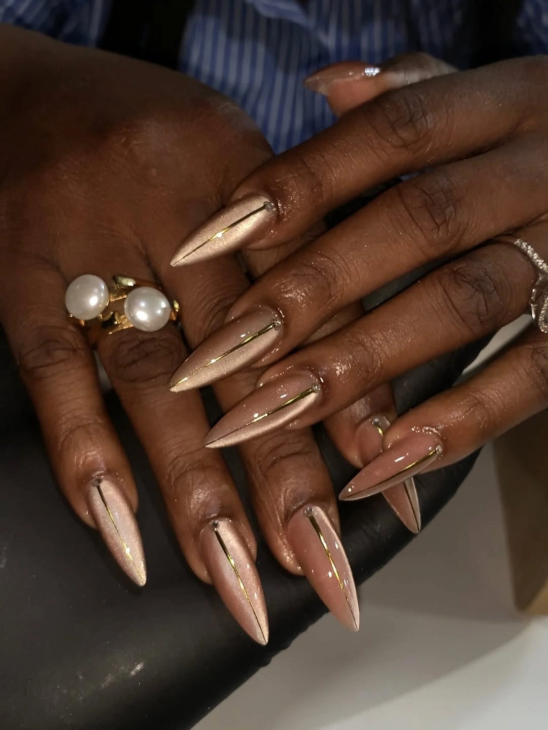 Long stiletto nude nails with fine champagne metallic lines