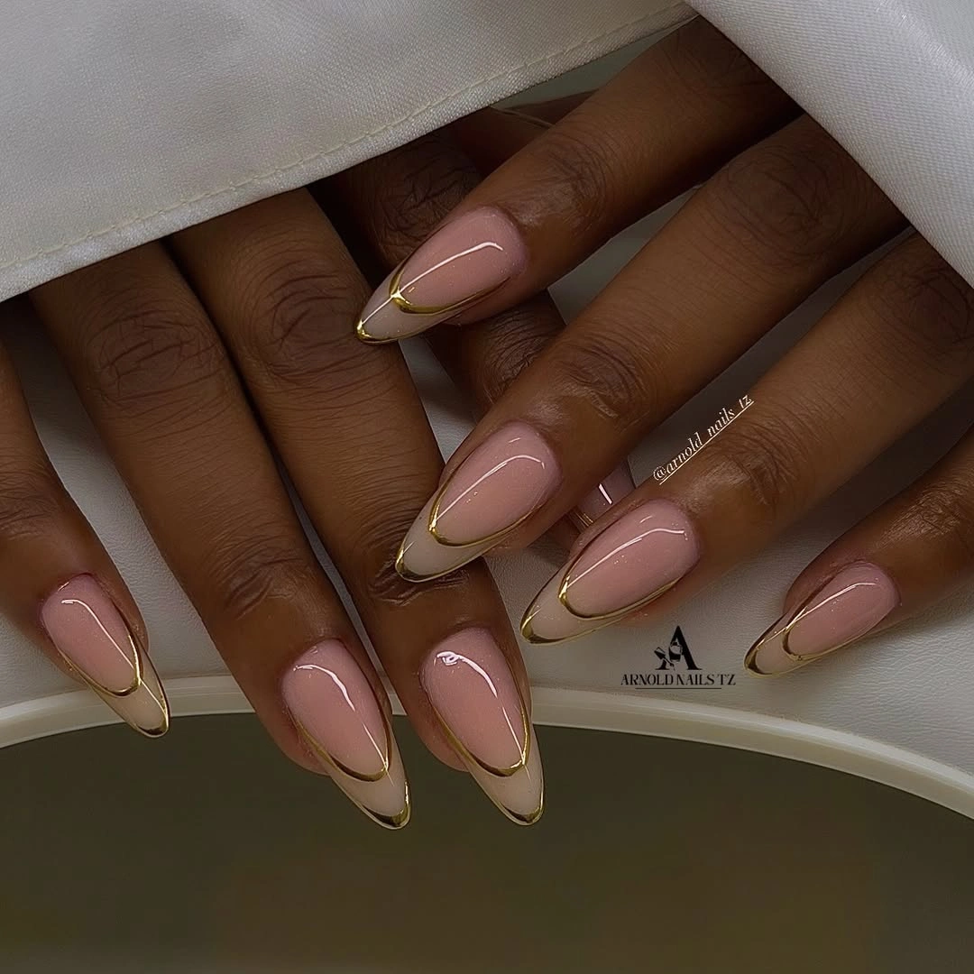 Long almond nude nails with delicate gold contour lines