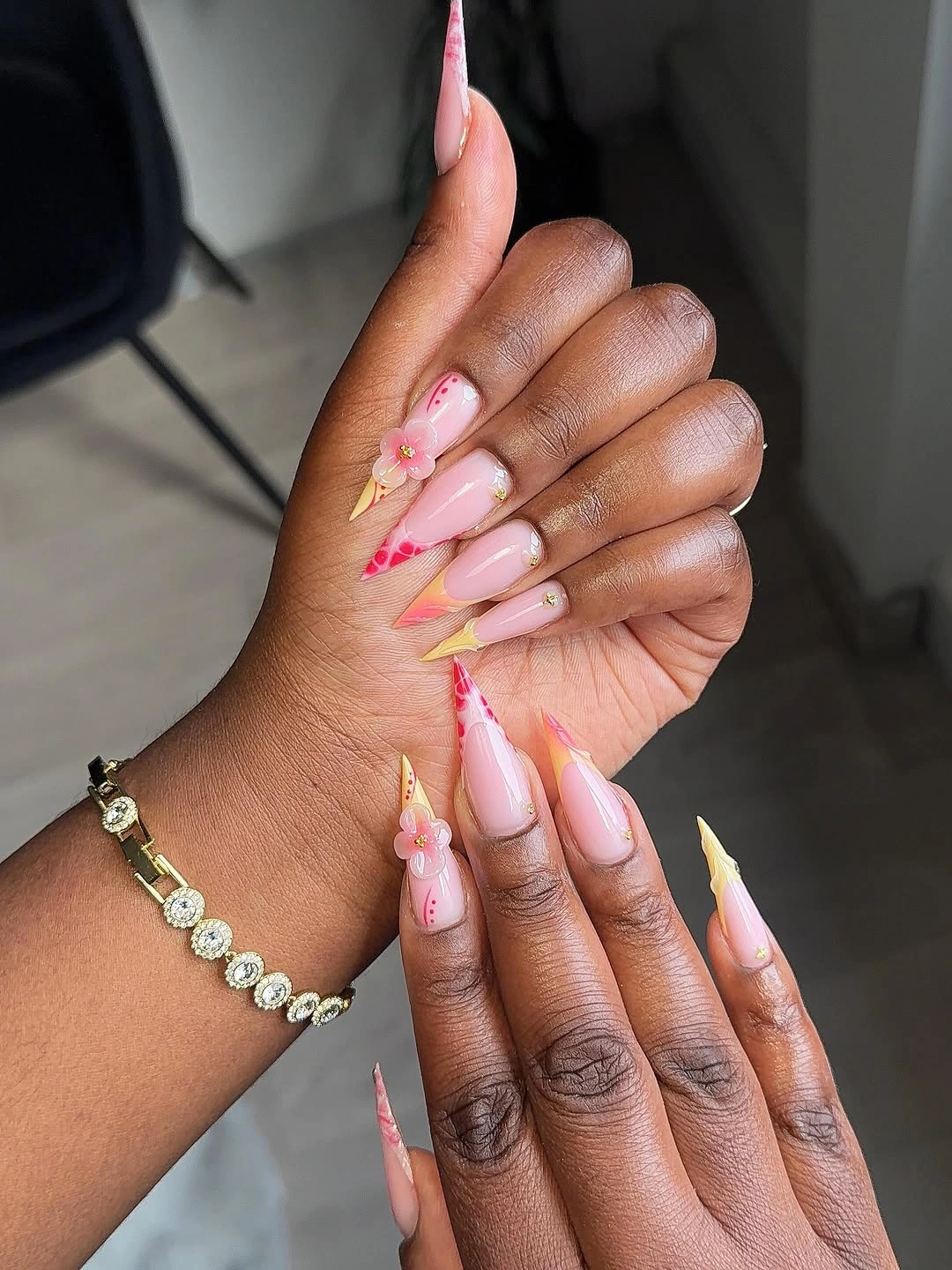 Long pink stiletto nails with yellow tips and flowers