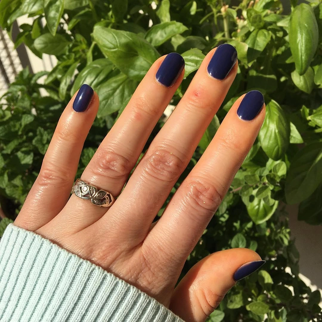 Short rounded nails in a glossy deep navy blue shade