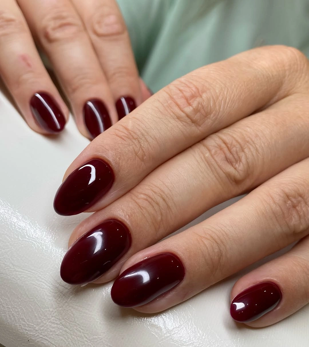 Glossy deep burgundy rounded nails in a compact shape