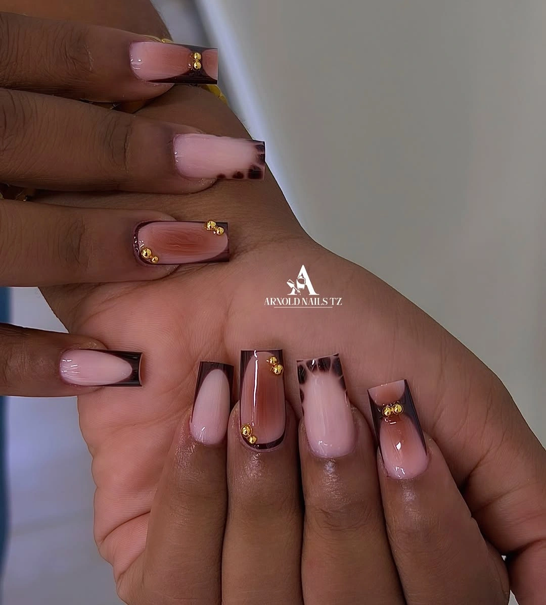 Pink square nails with brown framed tips and gold accents